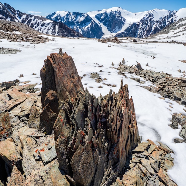 Paesaggio dell'altopiano con pietre affilate di forma insolita. Fantastico paesaggio montano panoramico con grandi pietre appuntite incrinate in mezzo alla neve sotto il cielo blu alla luce del sole. Rocce taglienti.