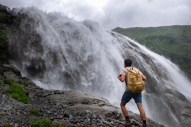 Paesaggio della cascata e viaggiatore maschio che gode della vista della cascata