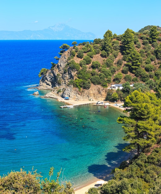 Paesaggio della costa del Mar Egeo con acqua color acquamarina e Monte Athos nella nebbia (Calcidica, Grecia). Un'immagine del punto di tre colpi. Persone irriconoscibili.