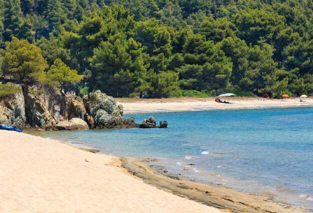 Paesaggio della costa del Mar Egeo estivo con spiaggia sabbiosa (Sithonia, Halkidiki, Grecia). Persone irriconoscibili.