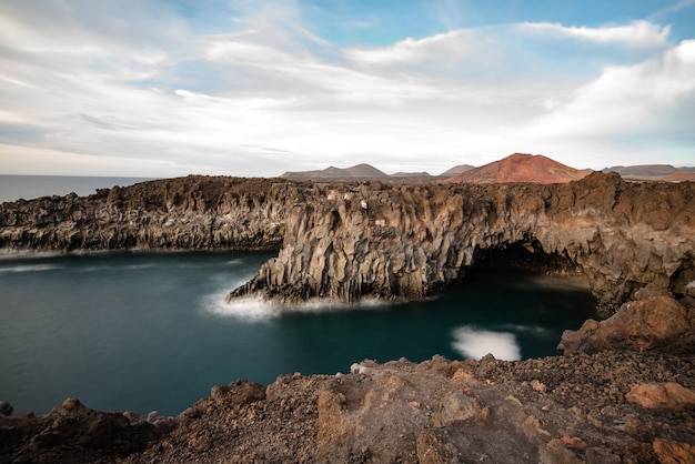 Paesaggio della costa vulcanica di Los Hervideros con grotte marine dove le onde si infrangono.