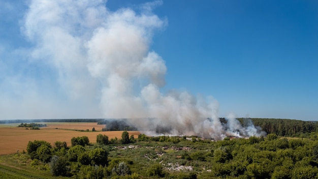 Paesaggio della discarica che brucia in campagna. Problema di inquinamento ecologico