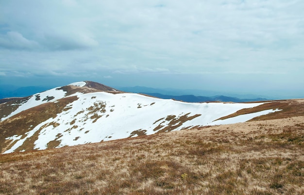 Paesaggio della grande vetta innevata delle montagne in primavera nella giornata nuvolosa