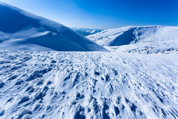 Paesaggio della valle e delle montagne di inverno della neve il giorno soleggiato