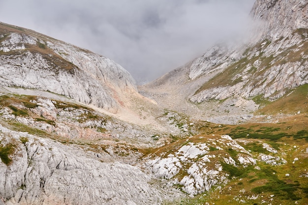Paesaggio di montagna - gola alpina rocciosa parzialmente nascosta da una nuvola