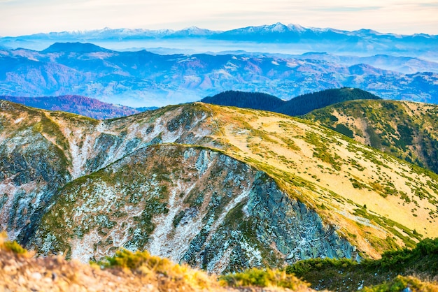 Paesaggio di montagne con diverse gamme di terreni e cielo al tramonto