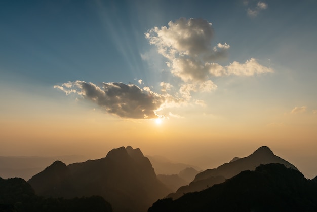 Paesaggio di montagne, nuvole con raggi solari al tramonto