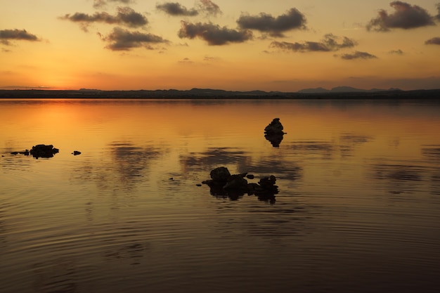 Paesaggio di un lago al tramonto con sagome di pietre