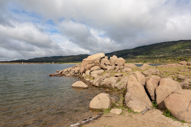 Paesaggio di un lago con un primo piano di rocce di granito accatastate sulla riva, rocce