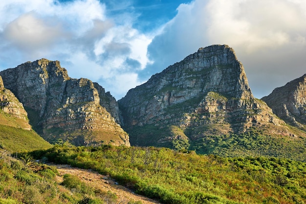 Paesaggio di una montagna a Città del Capo in Sud Africa durante il giorno Cima rocciosa con vegetazione contro il cielo nuvoloso Al di sotto della popolare attrazione turistica e del sentiero escursionistico avventuroso vicino alla montagna della tavola