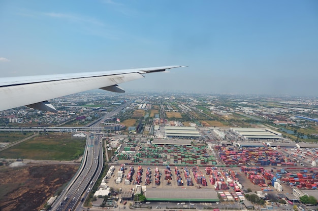 Paesaggio distante con un bellissimo campo fluviale ed edifici contro il cielo azzurro sconfinato sotto l'ala di un aeroplano volante