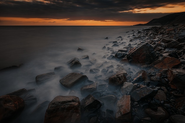 Paesaggio drammatico del tramonto a lunga esposizione con la costa rocciosa del Mar Nero