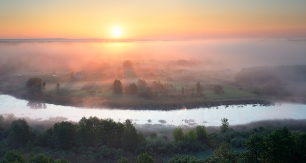 Paesaggio estivo con un fiume e una nebbia mattutina