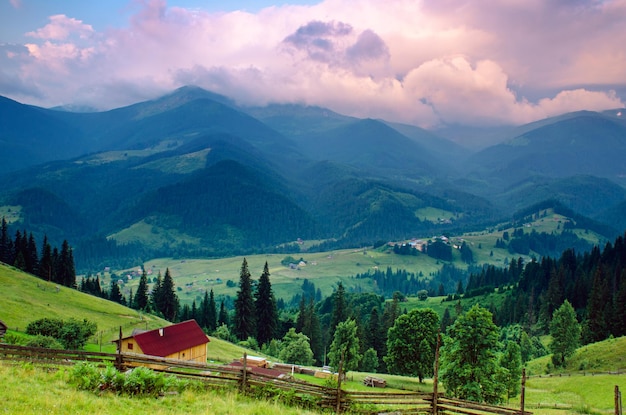 Paesaggio estivo delle montagne dei Carpazi con cielo nuvoloso e villaggio, sfondo di viaggio estivo naturale