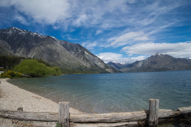 Paesaggio idilliaco della Patagonia Argentina. Lago tra montagne, spiaggia, vegetazione e cielo nuvoloso.