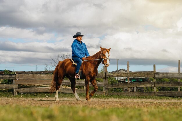 Paesaggio in un ranch con un uomo latino a cavallo al tramonto.