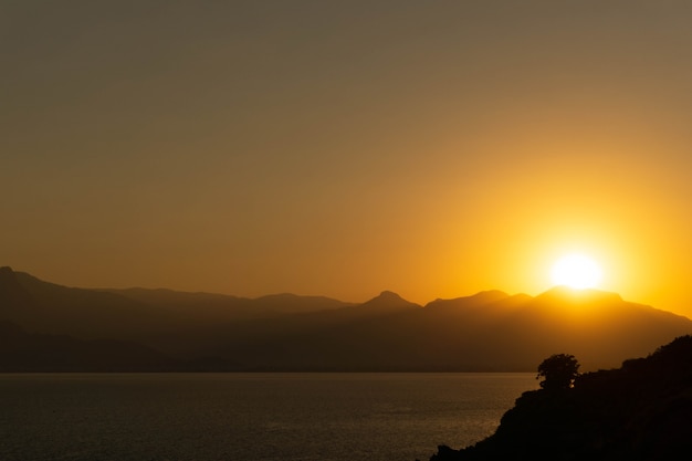 Paesaggio incredibilmente bello del sole al tramonto sullo sfondo delle montagne, giorno d'estate