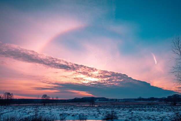 Paesaggio innevato invernale. Campo innevato al tramonto