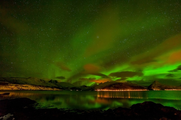 Paesaggio invernale con aurora, mare con riflesso del cielo e montagne innevate