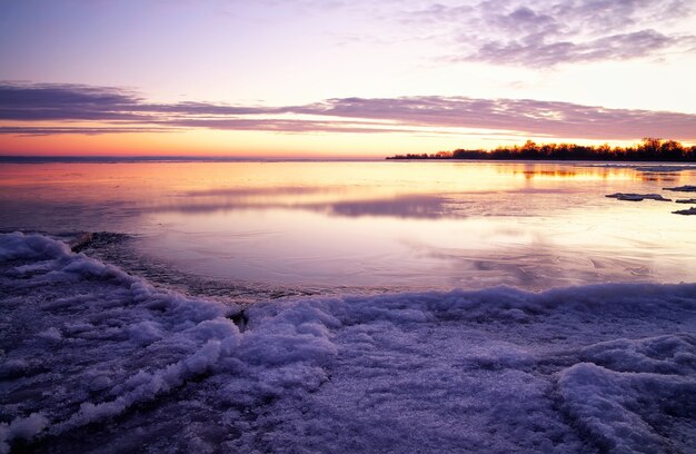 Paesaggio invernale con lago e cielo infuocato al tramonto. Composizione della natura.