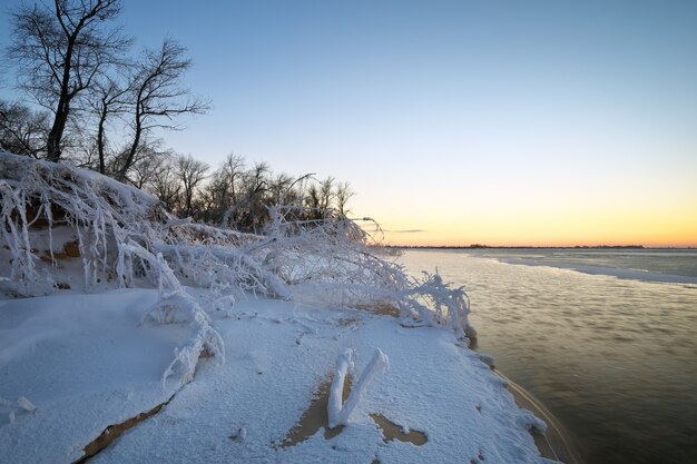 Paesaggio invernale con lago ghiacciato e cielo al tramonto. Composizione della natura.