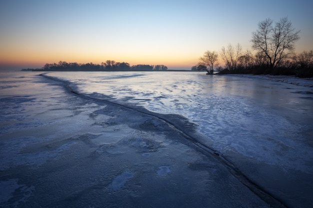 Paesaggio invernale con lago ghiacciato e cielo al tramonto. Composizione della natura.