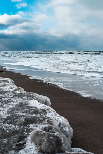 Paesaggio invernale con mare ghiacciato e spiaggia ghiacciata Paesaggio marino drammatico Tempesta e tempo di neve