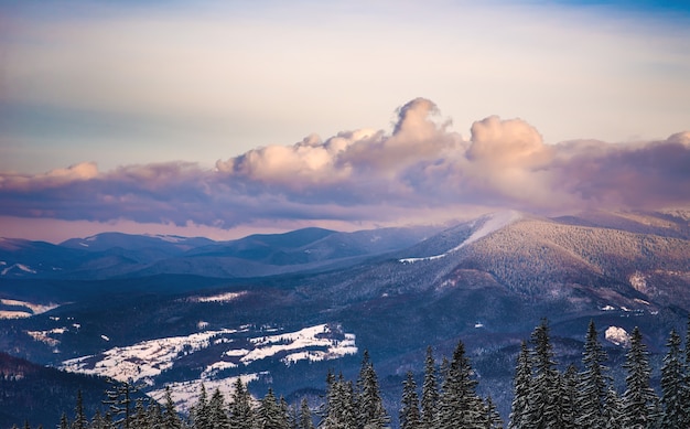 paesaggio invernale di montagne e foreste in inverno con un cielo al tramonto e nuvole rosa