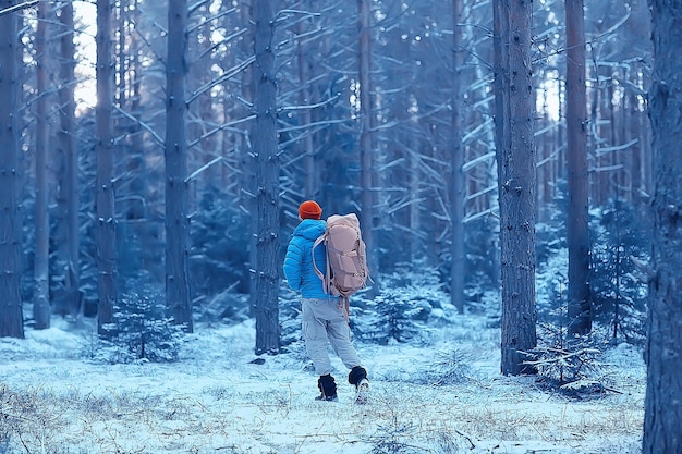paesaggio invernale foresta zaino uomo / viaggiatore in abiti invernali moderni nella foresta, viaggiando in montagna europa, svizzera inverno