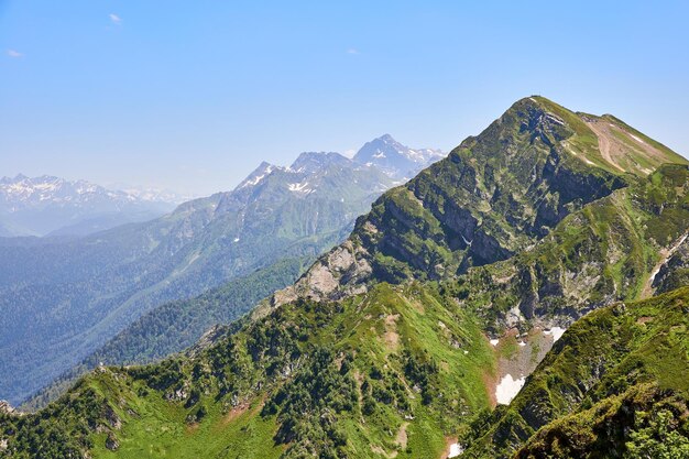 Paesaggio luminoso di montagna con montagne innevate, cielo azzurro e nuvole