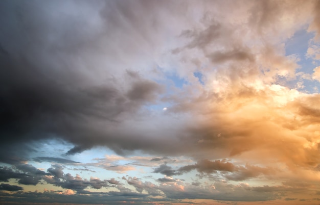 Paesaggio luminoso di nuvole scure sul cielo giallo al tramonto in serata.