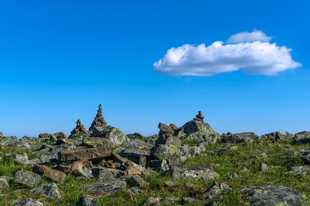 Paesaggio luminoso di un altopiano di alta quota con piramidi di viaggiatori piegati ometti di pietre