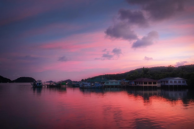 Paesaggio marino con barche da pesca cielo al tramonto luminoso e riflessi sull'acqua