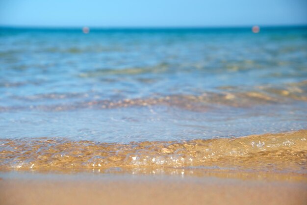 Paesaggio marino con superficie di acqua di mare blu con piccole onde ondulate che si infrangono sulla spiaggia di sabbia gialla Concetto di viaggio e vacanze