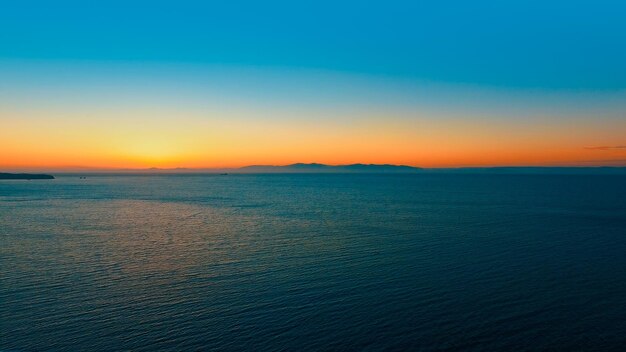 Paesaggio marino con un tramonto arancione all'orizzonte