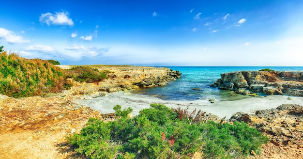 Paesaggio marino pittoresco con scogliere rocciose bianche, isolette e faraglioni vicino alla spiaggia di Conca Specchiulla