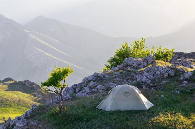 Paesaggio mattutino con una tenda. Campeggio nelle montagne primaverili