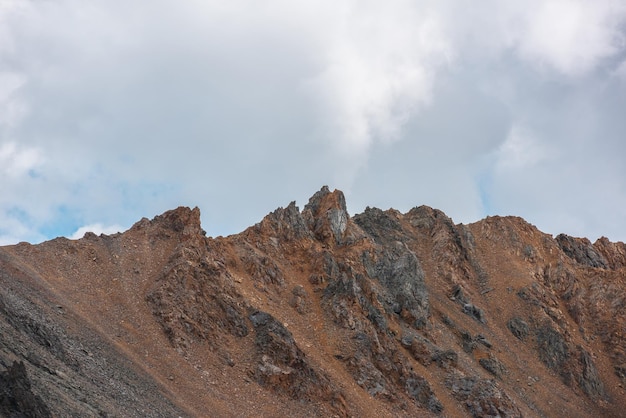 Paesaggio minimalista con un'alta cresta di montagna rocciosa sotto il cielo nuvoloso Scenario minimalista con pinnacolo su una grande parete di montagna con tempo nuvoloso Minimalismo semplice con rocce appuntite e cima di una montagna a picco