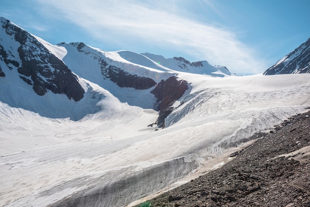 Paesaggio montano panoramico con grande ghiacciaio alla luce del sole Incredibile scenario innevato con lingua glaciale sotto i cirri Bella vista alpina sulle cime delle montagne innevate ad altissima quota in una giornata di sole