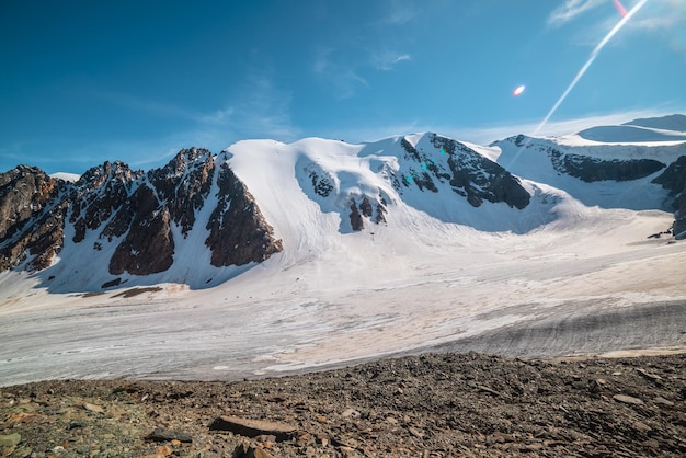 Paesaggio montano panoramico con grande ghiacciaio alla luce del sole Scenario fantastico con lingua glaciale sotto il sole nel cielo blu Splendida vista alpina sulle cime delle montagne innevate ad altissima quota in una giornata di sole