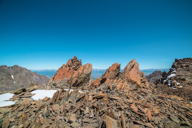 Paesaggio montano panoramico con vecchie rocce e pietre tra la neve alla luce del sole Incredibile scenario alpino con valori anomali in pietra in alta montagna sotto il cielo blu in una giornata di sole Rocce affilate ad altissima quota