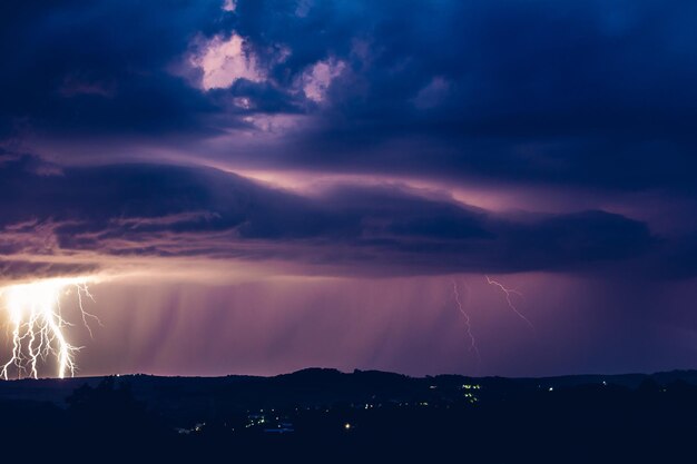Paesaggio notturno su uno sfondo di temporali Silhouette rurale e nuvole con lampi