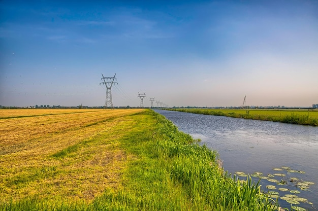 Paesaggio olandese con un canale e campi in erba con riflesso a specchio