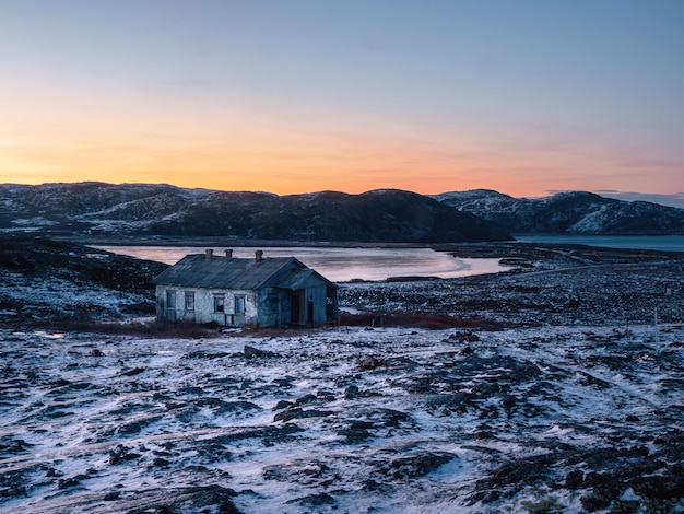 Paesaggio polare serale con una vecchia casa vicino a un lago