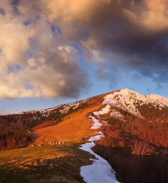 Paesaggio primaverile con case in legno in montagna. Insediamento dei pastori. Luce del sole al tramonto