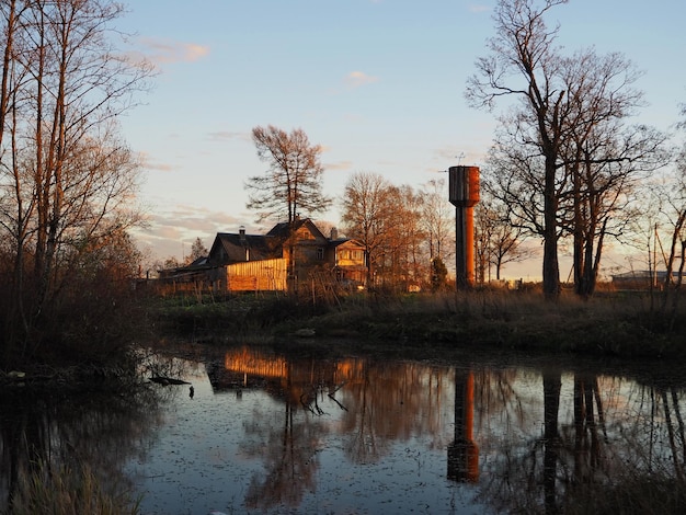 Paesaggio rurale Alberi della torre dell'acqua della vecchia casa e uno stagno al tramonto