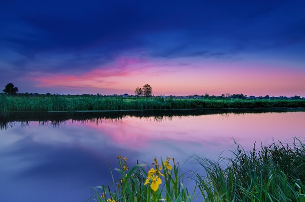 Paesaggio rurale dell'alba estiva con fiume e cielo colorato drammatico