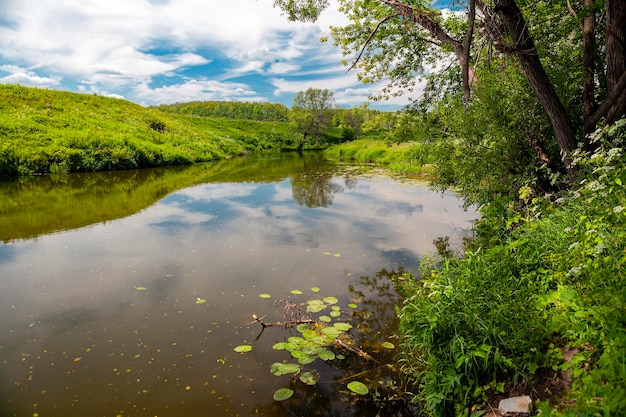 Paesaggio rurale in una giornata estiva sulla riva del fiume con un riflesso del cielo blu. Russia.