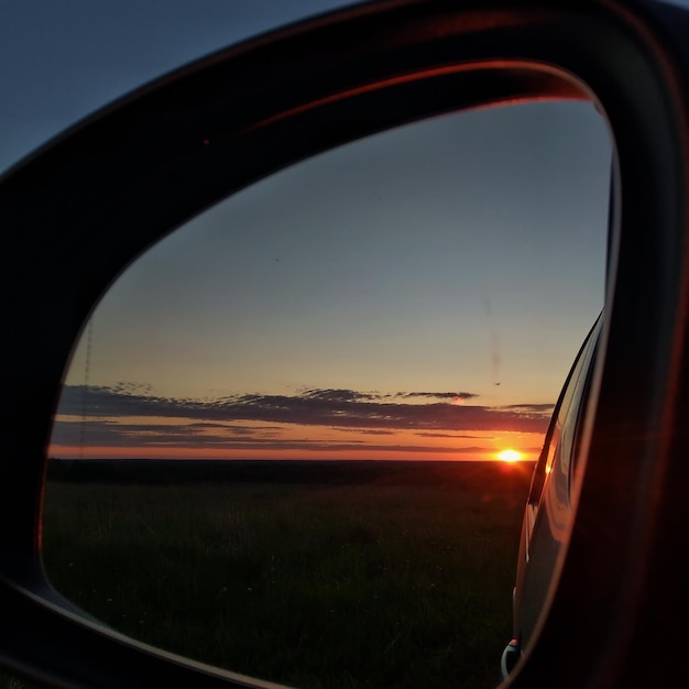 Paesaggio rurale. Riflessione di un tramonto colorato nello specchietto laterale di un'auto. regione di Leningrado,