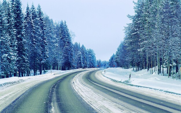 Paesaggio senza automobili in una strada di neve vuota in Finlandia. Viaggio di vacanza in autostrada con la natura. Scenario con viaggio invernale in viaggio per le vacanze per la ricreazione. Giro in moto in Europa. Trasporto su strada